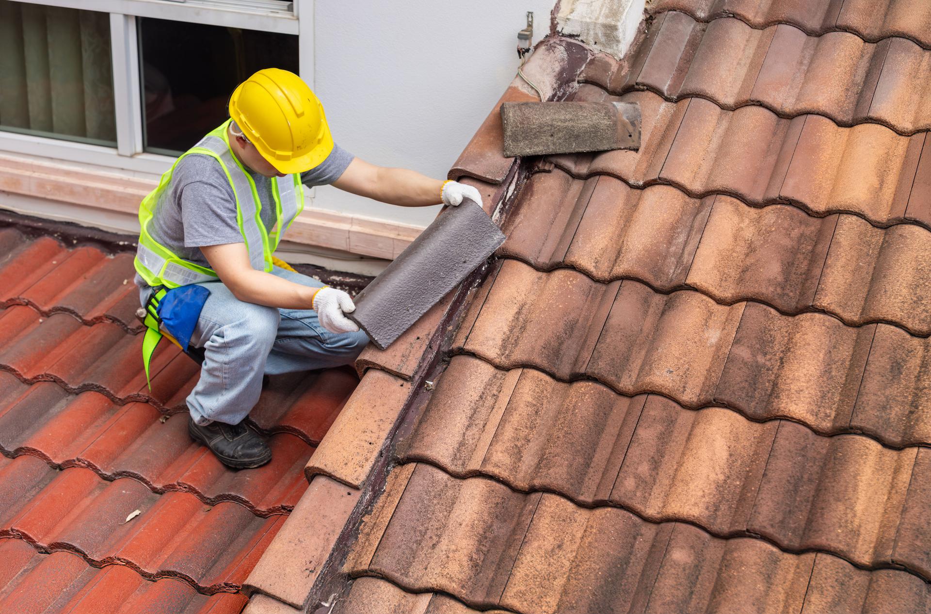 Worker fixing eaves and tiles of the old roof.