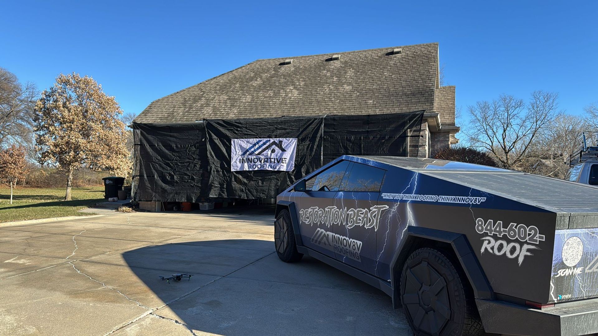 Innovative Roofing banner on garage with futuristic vehicle and drone on driveway.