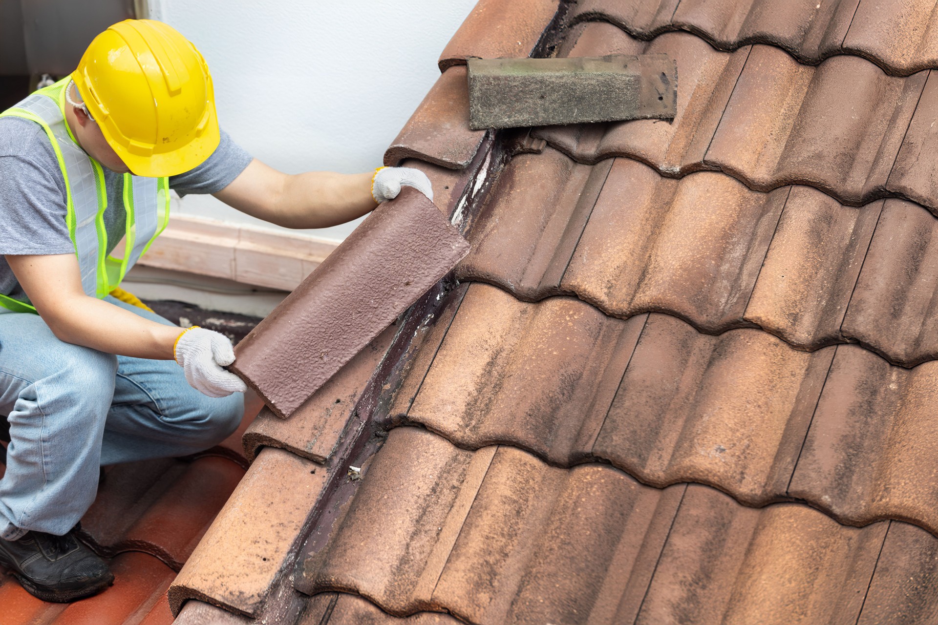 Worker fixing eaves and tiles of the old roof.