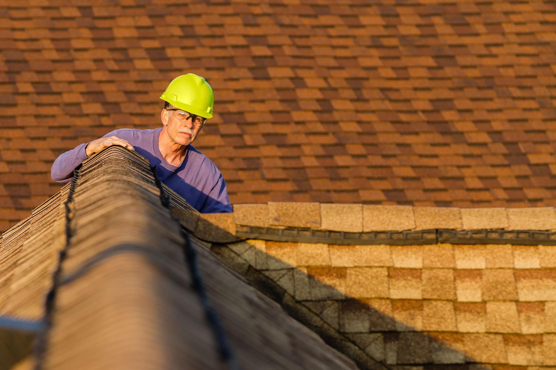 Home inspector examines architectural, asphalt shingled roof.